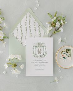 the wedding stationery is laid out on top of an envelope and some white flowers