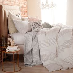 a bed with white linens and pillows in a bedroom next to a brick wall