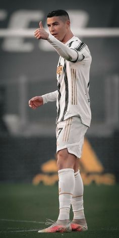 a man standing on top of a soccer field holding his hand up in the air