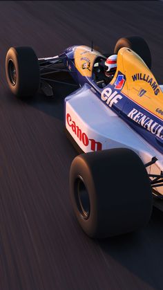 a yellow and blue racing car driving down a track