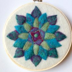 a colorful flower made from felt is hanging on a wall ornament in the shape of a circle