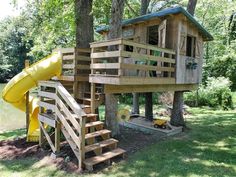 there is a tree house with a slide in the yard