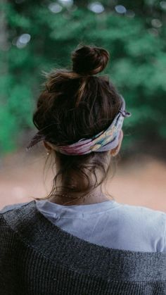 a woman with her hair in a bun is looking down at something on the ground