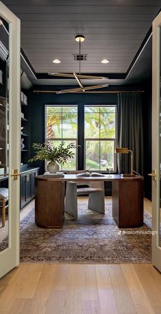 a room that has a desk in the middle of it with two chairs and a potted plant