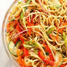 a glass bowl filled with noodles and vegetables