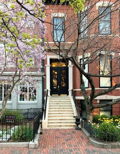 the front entrance to an apartment building with steps leading up to it and flowering trees in bloom