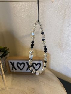 a beaded necklace hanging from a hook on a table next to a vase with flowers