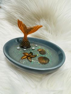 a blue plate with shells and a butterfly on the top is sitting on white fur