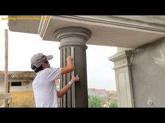 a man that is standing next to a pillar with his hand on the top of it