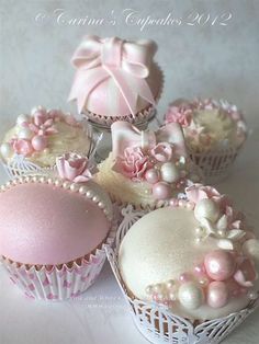 some cupcakes with pink frosting and bows on them are sitting in baskets