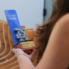 a woman holding an award in front of her face and looking at the back of her head