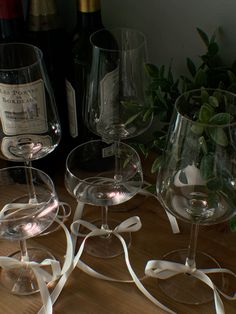 three wine glasses sitting on top of a wooden table