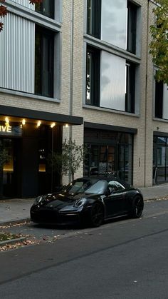 a black sports car parked in front of a building on the side of a street