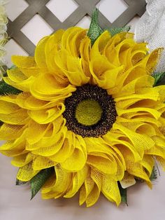 a large yellow sunflower with green leaves on it's head and stems in the center