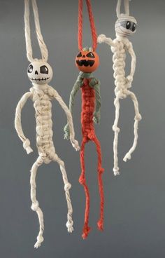 three halloween decorations hanging from strings in the shape of skeletons