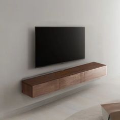 a flat screen tv mounted to the side of a white wall in a living room