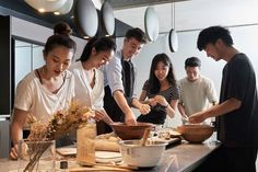 a group of people standing around a kitchen preparing food on top of a countertop