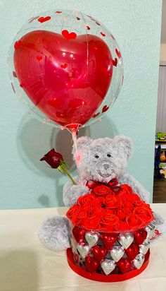 a teddy bear holding a heart shaped balloon in a basket filled with roses and hearts