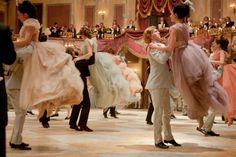 a man in a tuxedo dancing with a woman in a pink dress and other people around him