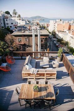 an outdoor patio with wooden furniture overlooking the ocean and cityscape in the background