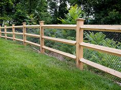 a wooden fence in the middle of a grassy field