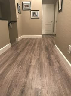 an empty room with wood flooring and pictures on the wall in it's corner