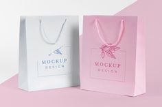 two paper bags with necklaces on them sitting side by side against a pink and white background