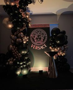 black and silver balloons are on display in front of a sign that reads versace