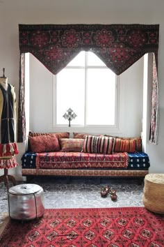 a couch sitting in front of a window next to a rug