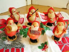 several small figurines are sitting on a table with red cloths and decorations