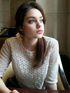 a young woman sitting at a table with her eyes closed