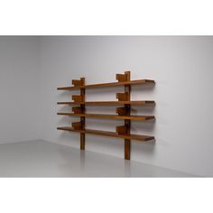 a wooden shelf sitting on top of a white floor next to a wall filled with shelves