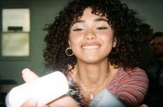 a woman is smiling and holding something in her hand