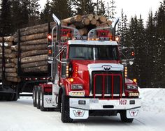 a red semi truck hauling logs in the snow