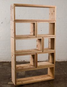 a wooden shelf sitting on top of a cement floor next to a white brick wall