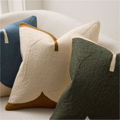 three pillows sitting on top of a white couch