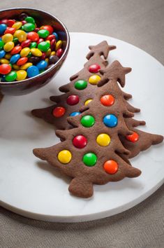 two decorated cookies sitting on top of a white plate next to a bowl of candy