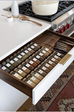 an open drawer in a kitchen filled with spices and seasonings on top of a rug