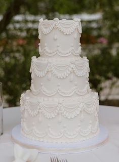 a white wedding cake sitting on top of a table next to a knife and fork