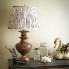 a lamp sitting on top of a table next to vases and other items in front of a white wall