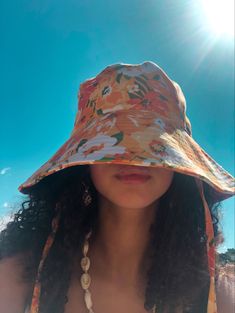 a woman wearing a sun hat on top of her head with the sun shining behind her