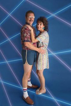 a man and woman are standing together in front of a blue background with white lines