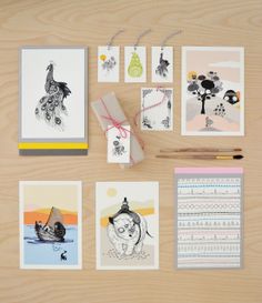 various cards and stationery items displayed on wooden surface with pen, paper clippings and pencil