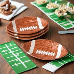 three plates with footballs on them are sitting on a table next to snacks and crackers