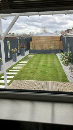 a backyard with grass and stepping stones is seen from the window in this house's back yard