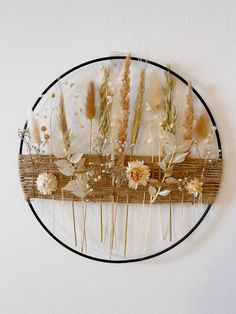 an art piece with dried flowers and plants on it's side hanging on the wall