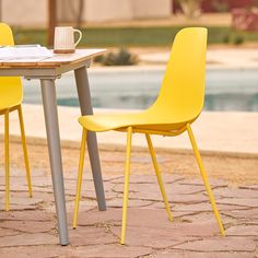 two yellow chairs sitting at a table next to a pool