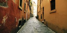 an alleyway with cobblestone stone floors and old buildings on either side in the city