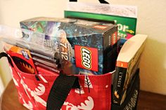 a bag filled with books and snacks on top of a wooden table next to a wall