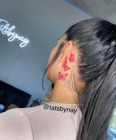 a woman with a red butterfly tattoo on her left side of her neck and behind her ear